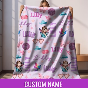 Op de afbeelding: Een lichtpaarse deken met een herhalend patroon van harten, vlinders, dobbelstenen, cowboyhoeden en een fee&euml;nillustratie. De naam "Lilly" staat meerdere keren op de deken. De onderkant van de deken heeft de tekst "CUSTOM NAME".