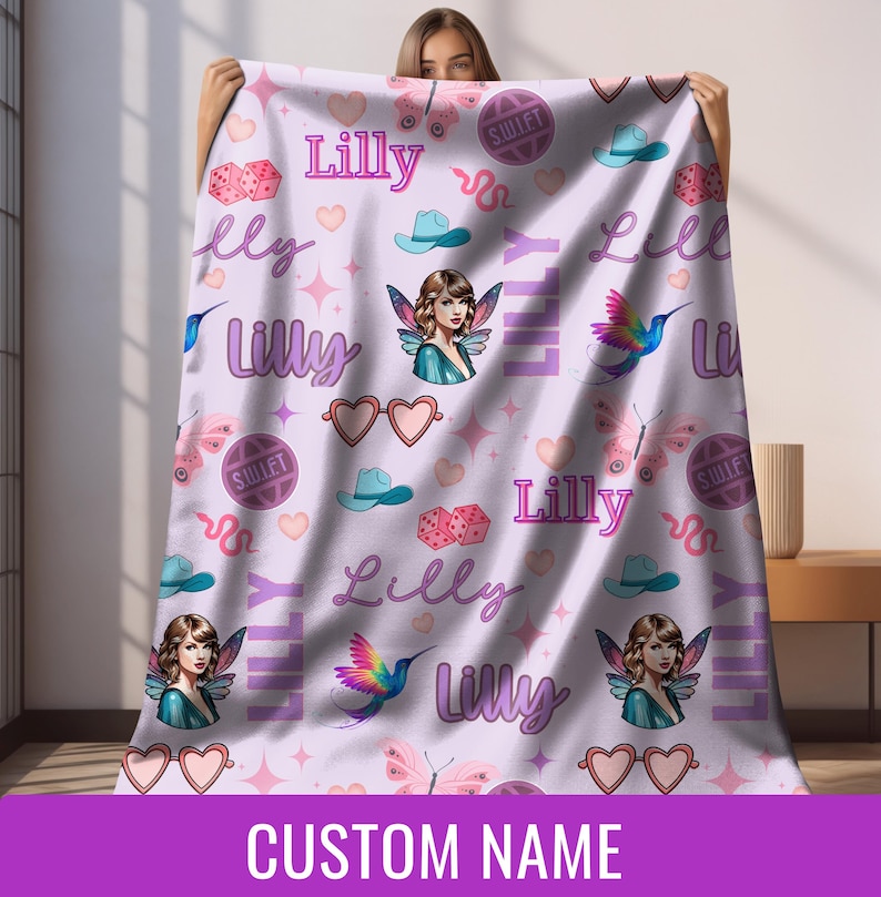 Op de afbeelding: Een lichtpaarse deken met een herhalend patroon van harten, vlinders, dobbelstenen, cowboyhoeden en een fee&euml;nillustratie. De naam "Lilly" staat meerdere keren op de deken. De onderkant van de deken heeft de tekst "CUSTOM NAME".