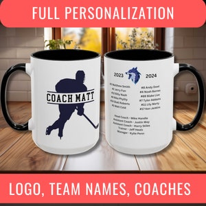 May include: Two white ceramic mugs with black handles. The mug on the left has a black silhouette of a hockey player with the text "COACH MATT". The mug on the right has a wolf logo and text listing team names and coaches for the 2023 and 2024 seasons.