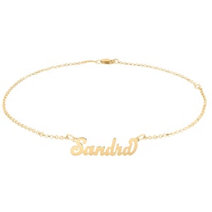 Può includere: Un braccialetto per caviglia in catena dorata con il nome "Sandra" scritto in corsivo.