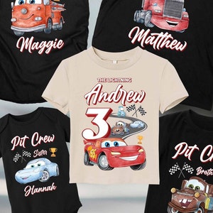 May include: A set of five black t-shirts with a Cars-themed design. The shirts feature a red race car, a red fire truck, and the text "Pit Crew" with different names. The shirts are for a family of five, including a birthday boy.