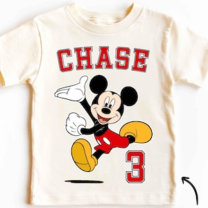 May include: A white vintage t-shirt with a red and black Mickey Mouse graphic, the name "CHASE" in red block letters, and the number "3" in red block letters.