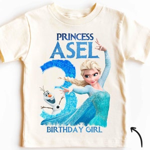 Könnte beinhalten: Ein weißes Vintage-T-Shirt mit einem blauen und weißen Motiv von Elsa aus Frozen. Das Motiv enthält den Text "Princess Asel Birthday Girl".