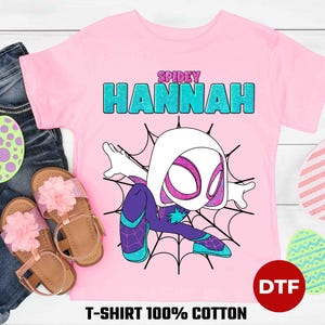 May include: Pink t-shirt with a cartoon image of Spider-Gwen, a female superhero with white and black costume, and the text "SPIDEY HANNAH" in blue and green glitter letters. The shirt is made of 100% cotton and has a DTF print.