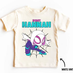 May include: White vintage t-shirt with a cartoon image of a female superhero in a spider web. The text "SPIDEY HANNAH" is printed on the shirt.