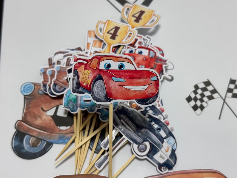 May include: A set of 12 cupcake toppers featuring characters from the Cars movie. The toppers include Lightning McQueen, Mater, and other characters. The toppers are printed on cardstock and have wooden sticks attached to the back. The toppers are perfect for decorating cupcakes for a Cars-themed party.