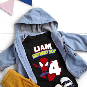 May include: Black t-shirt with a red and blue Spiderman graphic, the text "Liam Birthday Boy" in yellow and red letters, and the number "4" in white. The shirt is on top of a blue hooded jacket and yellow pants.
