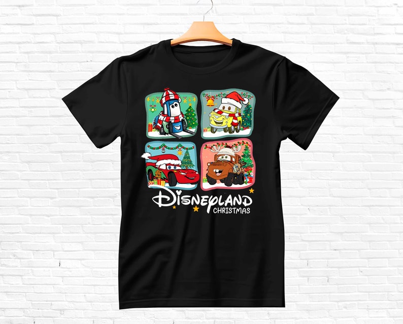 May include: Black t-shirt with a Christmas-themed design featuring characters from the Disney Pixar movie Cars. The design includes Lightning McQueen, Mater, and other characters in festive settings. The text "DISNEYLAND CHRISTMAS" is printed below the characters.