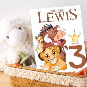 May include: A birthday card featuring the characters Pumbaa, Timon, and Simba from Disney's The Lion King. The card is white with brown text that reads "The King Lewis Turns 3". A gold crown is above the number 3.