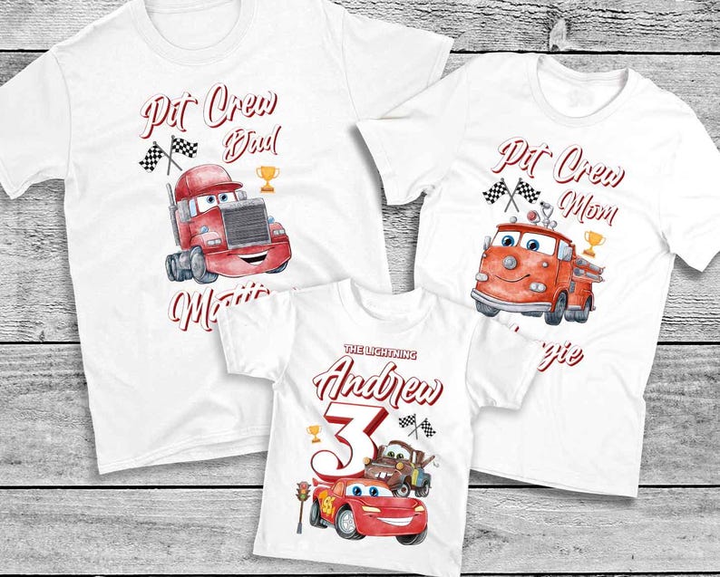 May include: Three white t-shirts with a Cars theme. The shirts feature a red race car, a red fire truck, and a red semi-truck. The text on the shirts reads "Pit Crew Dad", "Pit Crew Mom", and "The Lightning Andrew 3".
