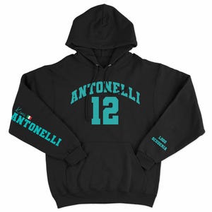 Pode incluir: Camisola de capuz preta com o texto "ANTONELLI 12" em azul turquesa na frente. A manga esquerda tem o texto "Kimi ANTONELLI" em azul turquesa com uma pequena bandeira italiana.