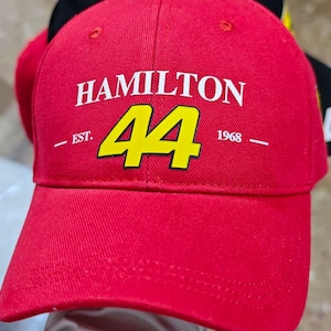 May include: Red baseball cap with a white "HAMILTON" logo and a yellow number "44" in the center. The text "EST. 1968" is printed below the number.