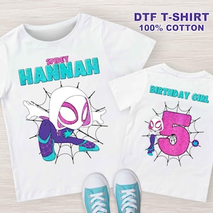 May include: Two white t-shirts with a Spider-Gwen design. The first shirt has the text "SPIDEY HANNAH" in turquoise glitter. The second shirt has the text "BIRTHDAY GIRL" in turquoise glitter and a pink glitter number 5.