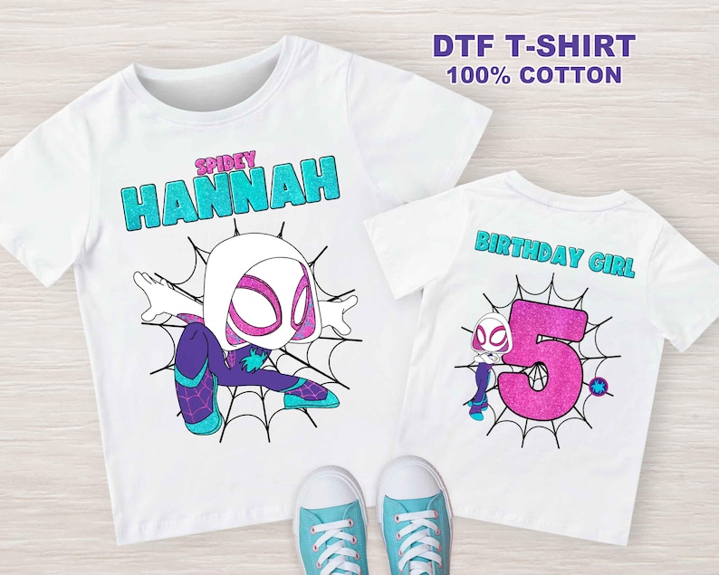 May include: Two white t-shirts with a Spider-Gwen design. The first shirt has the text "SPIDEY HANNAH" in turquoise glitter. The second shirt has the text "BIRTHDAY GIRL" in turquoise glitter and a pink glitter number 5.