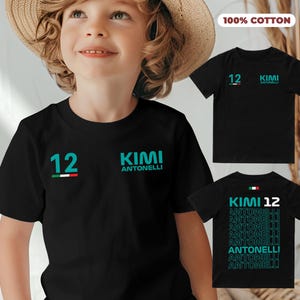 Könnte beinhalten: Ein schwarzes T-Shirt mit dem Text "KIMI ANTONELLI" und der Nummer "12" in Türkis. Das Shirt hat ein kleines italienisches Flaggenemblem. Die Worte "100% COTTON" sind in einem rosa Rechteck aufgedruckt. Zusätzliche Shirts werden angezeigt.