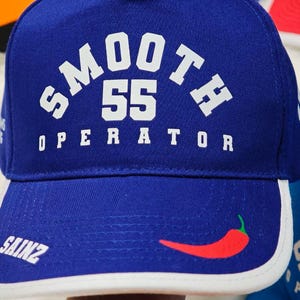 May include: A blue baseball cap with a white brim and a white logo that says "SMOOTH 55 OPERATOR" with a red chili pepper on the front.