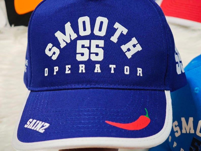 May include: A blue baseball cap with a white brim and a white logo that says "SMOOTH 55 OPERATOR" with a red chili pepper on the front.