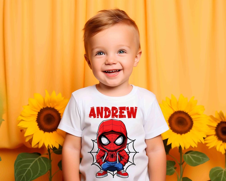 May include: A white t-shirt with a red and blue cartoon Spider-Man graphic and the name "ANDREW" printed in red letters.