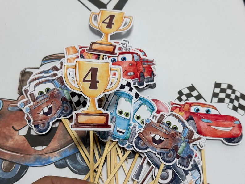 May include: A set of 10 cupcake toppers featuring cartoon characters from the Cars movie franchise. The toppers include Mater, Lightning McQueen, and a trophy with the number 4 on it. The toppers are printed on cardstock and attached to wooden skewers.