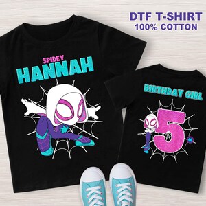 May include: Two black t-shirts with a white spider-woman graphic. The larger shirt says "SPIDEY HANNAH" and the smaller shirt says "BIRTHDAY GIRL" with the number 5.