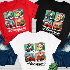 May include: Three t-shirts with a Christmas theme featuring characters from the Disney Pixar movie Cars. The shirts are red, black, and white. The design features a grid of four squares with a different character in each square. The text "Disneyland Christmas" is printed below the grid.