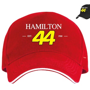 May include: Red baseball cap with a white brim and a white logo that says "HAMILTON EST. 44 1968" in yellow lettering.