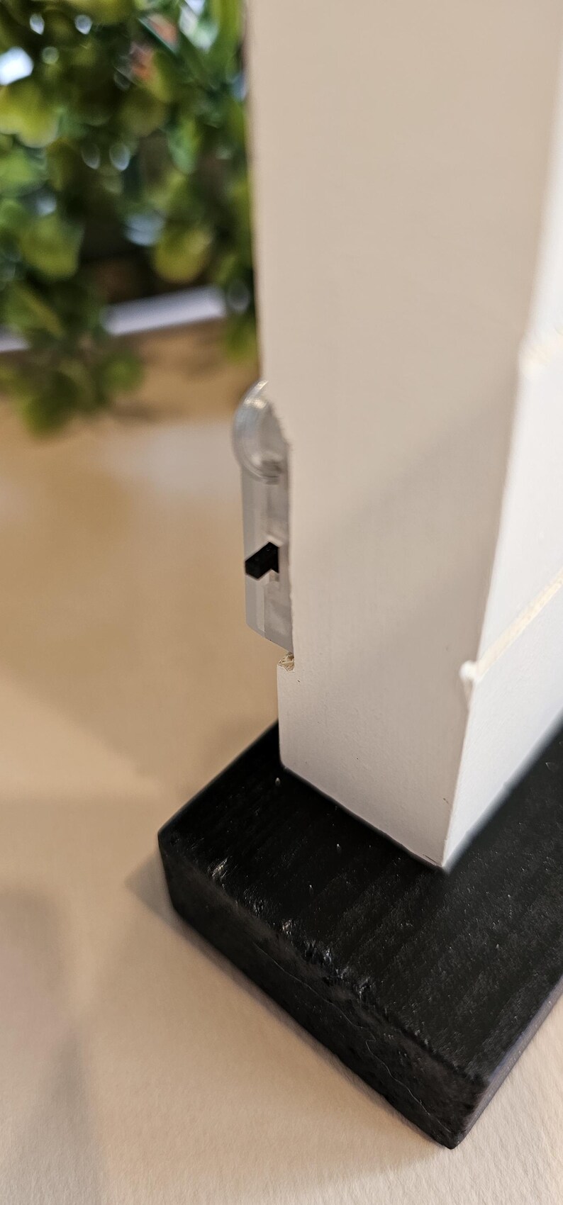 Puede incluir: Estante de madera blanca con base negra. El estante tiene un peque&ntilde;o pestillo de pl&aacute;stico transparente en el lateral.
