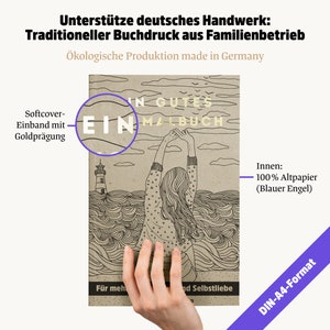 May include: A softcover coloring book with gold foil lettering, held by a hand. The cover features a line drawing of a person with arms raised, a lighthouse, and the text "EIN MALBUCH". The book is DIN-A4 format and made with 100% recycled paper.