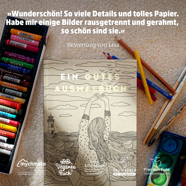 May include: A coloring book titled "EIN GUTES AUSMALBUCH" with a lighthouse and woman illustration. A box of colorful pastels and colored pencils are next to the book. The book is labeled as vegan and made with 100% recycled paper.