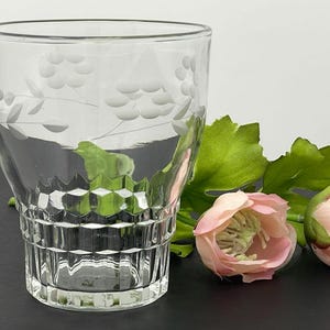 May include: A clear glass tumbler with a grapevine etched design. The glass has a textured, diamond-shaped pattern around the bottom.