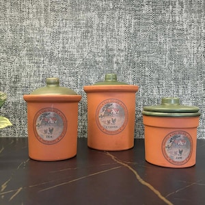 May include: A white ceramic mug with a black handle and the text "But First, Coffee" in a black, bold font. The mug is sitting on a wooden surface. The mug is approximately 4 inches tall.