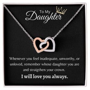 Può includere: Una collana d'argento con un ciondolo a forma di due cuori, un cuore è in oro rosa. La collana è presentata in una scatola nera con un messaggio che dice "To My Daughter" e "Whenever you feel inadequate, unworthy, or unloved, remember whose daughter you are and straighten your crown. I will love you always."