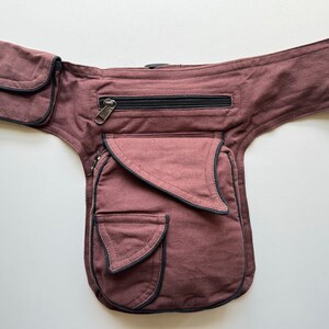 May include: A brown canvas fanny pack with multiple pockets and a zippered compartment. The pack has black trim around the edges.