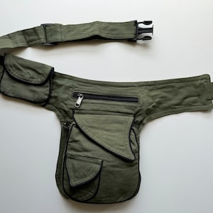 May include: A green canvas fanny pack with multiple pockets and a black zipper. The fanny pack has a black adjustable strap with a plastic buckle.