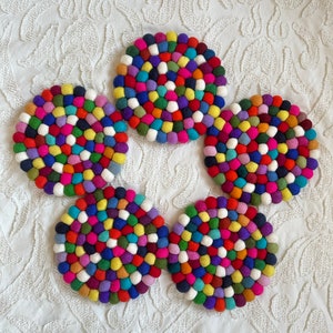 May include: Five colourful round felt coasters with a spiral pattern of small balls in various colours, including red, blue, green, yellow, and white.