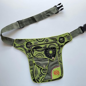 May include: A green and black fanny pack with a zipped pocket and a large pocket with a swirl design. The fanny pack has a green and black adjustable strap with a buckle.