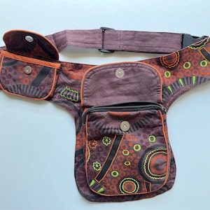 May include: A brown and black patterned fanny pack with a large pocket and two smaller pockets. The fanny pack has a brown adjustable strap with a black buckle.