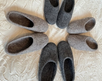 Puede incluir: Ocho zapatillas de fieltro gris dispuestas en círculo sobre un fondo blanco con un patrón floral. Las zapatillas son todas del mismo estilo, con la punta redondeada y un diseño sencillo.