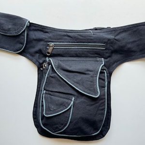 May include: A black canvas fanny pack with multiple pockets and a zippered compartment. The pack has light blue stitching around the edges of the pockets.