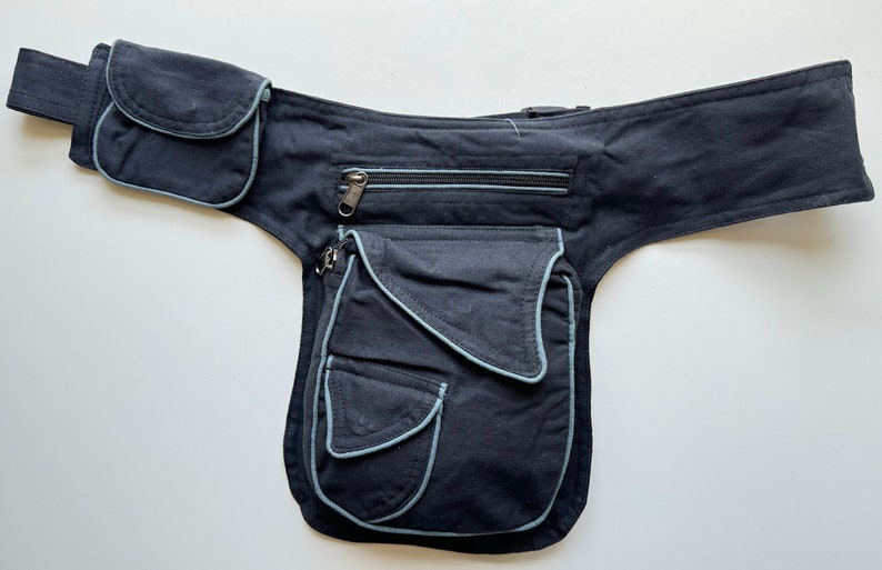 May include: A black canvas fanny pack with multiple pockets and a zippered compartment. The pack has light blue stitching around the edges of the pockets.