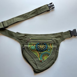 May include: An olive green fanny pack with a black buckle and adjustable strap. The front pocket has a colourful embroidered design with blue, yellow, and green accents. Includes a zipped pocket.