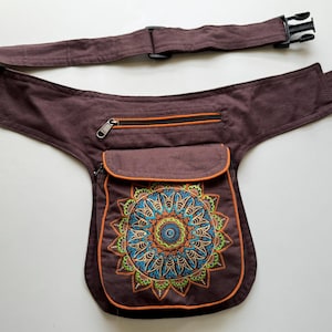 May include: A brown canvas fanny pack with a zipped pocket and a large embroidered mandala design in shades of orange, green, blue, and white.