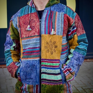 May include: A colorful patchwork hooded jacket with a zipper closure. The jacket features a variety of patterns and colors, including red, blue, green, yellow, and brown. The jacket has a sun and mushroom design on the front.