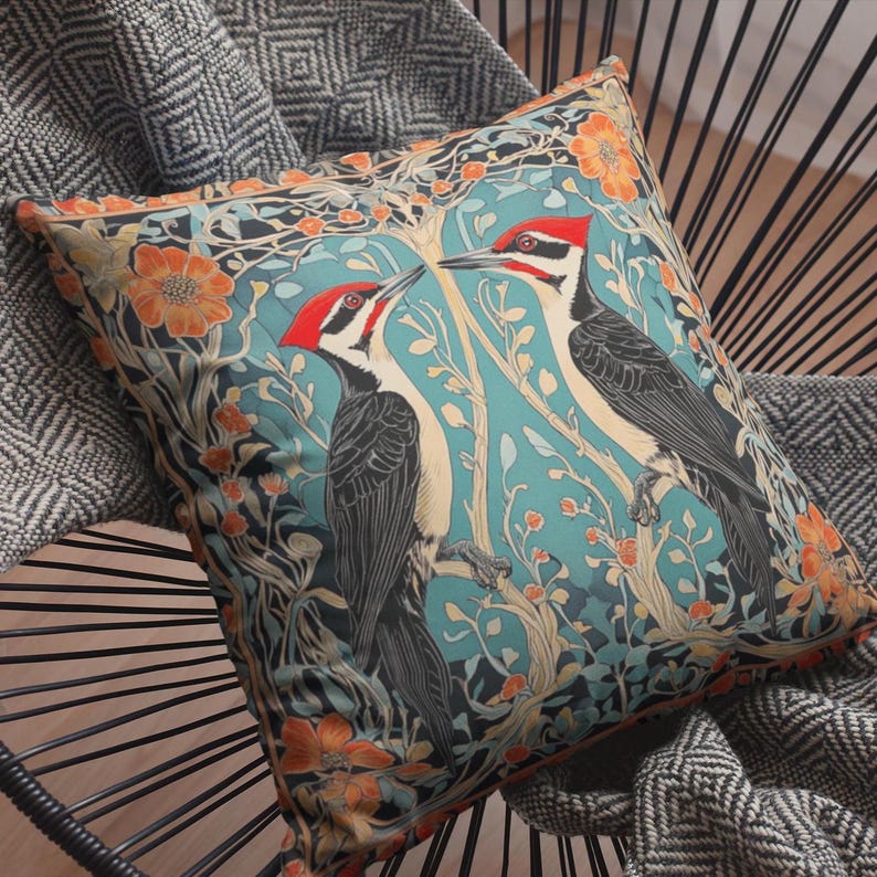 May include: A decorative throw pillow with a blue background featuring two red-headed woodpeckers perched on branches with intricate floral designs in shades of orange, red, and green.