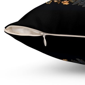 Puede incluir: Una almohada negra con cierre de cremallera. La almohada tiene un patr&oacute;n floral en tonos naranja y marr&oacute;n.