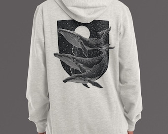 Peut inclure: Sweat à capuche gris clair avec un motif noir et blanc de trois baleines nageant dans un ciel étoilé. Les baleines sont dans un bouclier noir avec une lune blanche. Le sweat à capuche a une capuche et des manches longues.