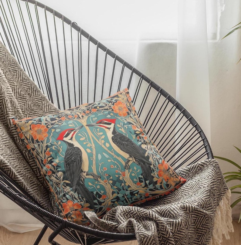 May include: A decorative throw pillow with a blue, green, and orange floral pattern featuring two black and red woodpeckers.