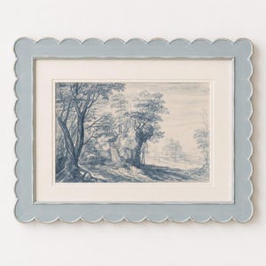 May include: A framed landscape print with a blue and white color scheme. The artwork depicts trees and a building in a forest setting. The frame is a light blue with a scalloped edge.