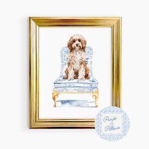 May include: Watercolor painting of a brown and white dog sitting on a blue and white patterned chair. The chair has a gold frame and the dog is looking at the viewer. The painting is framed in a gold frame and has the text "Prints & Pillows" in the bottom right corner.