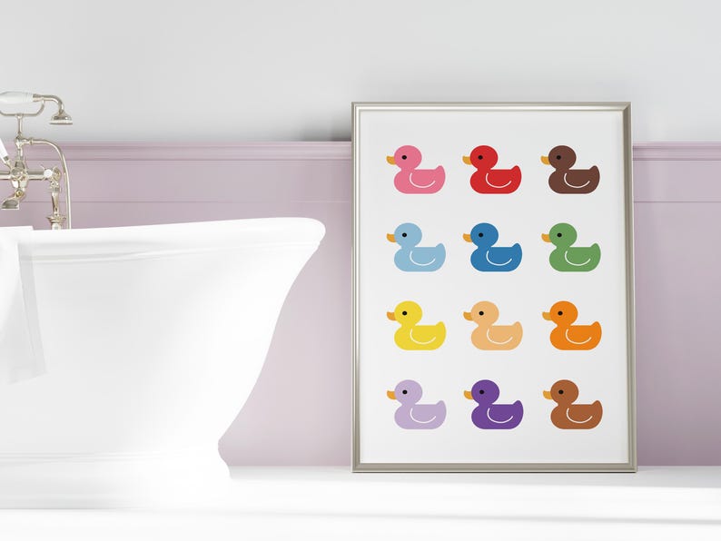 May include: A framed print with a white background and 12 colorful rubber duck illustrations. The ducks are arranged in four rows of three. Each duck is a different color, including pink, red, brown, blue, green, yellow, orange, purple, and brown.